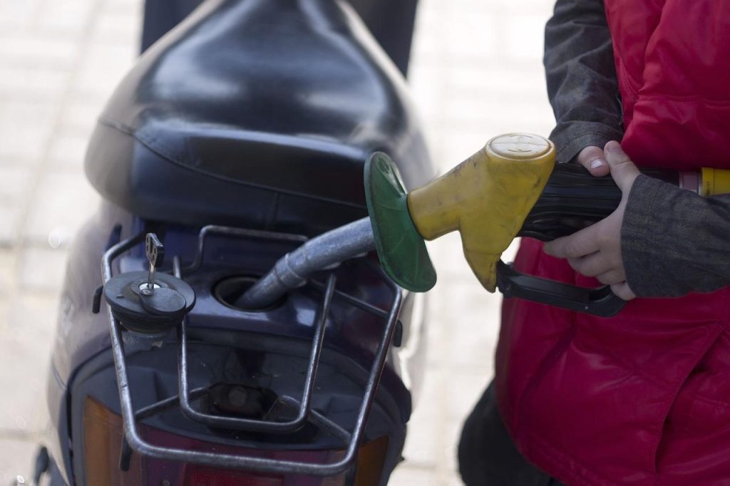 Forens in Ede bekijkt stijgende benzineprijs aan tankstation, symbool voor transport en milieukwesties